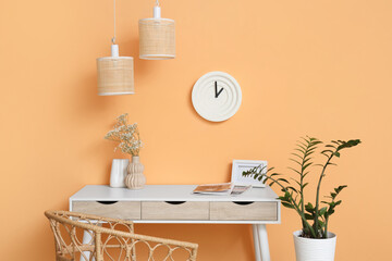 Clock on orange wall near workplace in room