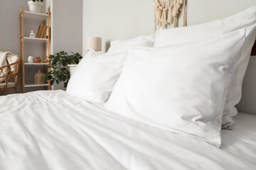 Cozy bed with white blanket and soft pillows in stylish bedroom, closeup