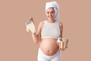 Beautiful young happy pregnant woman with massage mitten and brushes on beige background