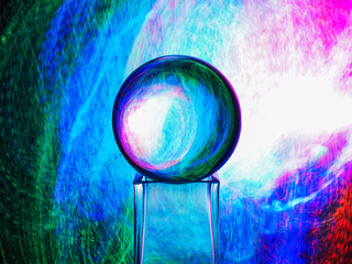 A clear glass ball is sitting on a pedestal. Colorful background. Abstract graphic background. Light effect. Planet in a space mood and feel.