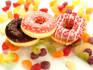 Pink and chocolate donuts on colorful sweet candy jelly. High level of sugar products. Popular international sweets.