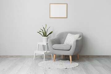 Armchair with coffee table, houseplant and photo frame near grey wall in living room