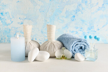 Set of spa accessories and orchid flower on light table near color wall