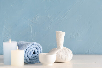 Set of spa accessories with burning candles on light wooden table near color wall