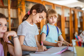 little school girls pupils sit on class in the school library