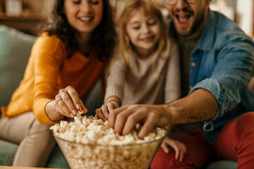 Family enjoying popcorn while watching a movie at home