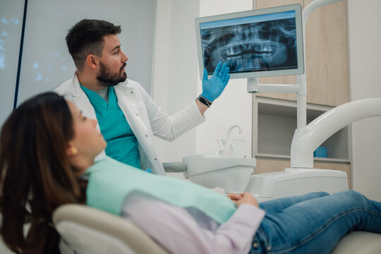 Dentist showing teeth x ray to patient in modern clinic