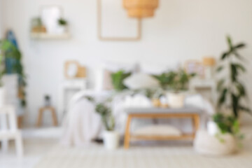 Blurred view of light bedroom with surfboard, soft bench and plants