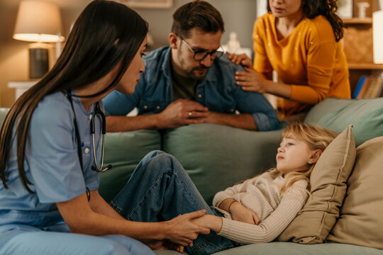 Pediatrician visiting ill child at home with worried parents