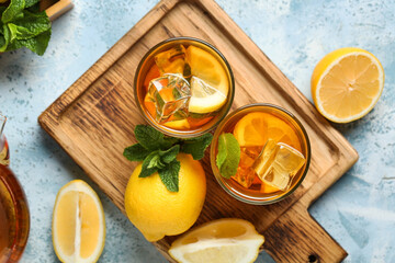 Glasses of lemon ice tea with mint and citrus fruits on blue background