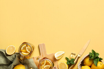 Mason jars of lemon ice tea with mint and citrus fruits on yellow background