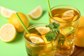 Glasses of lemon ice tea with mint on green background, closeup