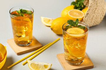 Glasses of lemon ice tea with mint and citrus fruits on grey background, closeup