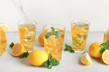 Fototapeta premium Glasses of lemon ice tea with mint and citrus fruits on white background