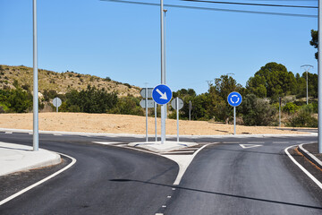 Roundabout with multiple directional signs on clear sunny day