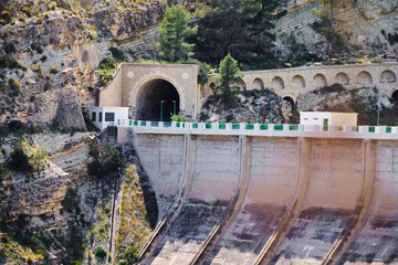 Majestic mountain dam with tunnel entrance surrounded by lush greenery