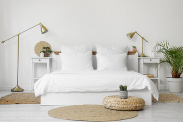 Interior of light room with white linen on bed, tables and lamps
