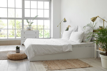 Interior of light room with white linen on bed, tables and lamps