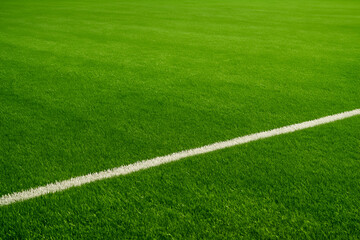 Obraz premium A vibrant close-up of a well-maintained soccer field, featuring lush green grass and a crisp white marking, ideal for capturing the essence of sports and outdoor activities.