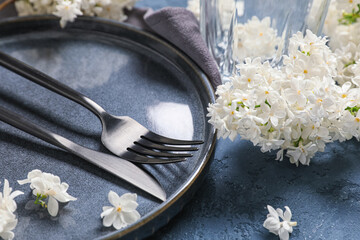 Beautiful table setting with white lilac flowers on blue background, closeup