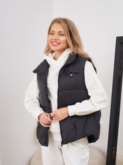 Fashionable woman poses in stylish vest indoors during bright daylight