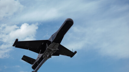 Military Drone in Flight Over Conflict Zone Displaying Advanced Weaponry and Surveillance...
