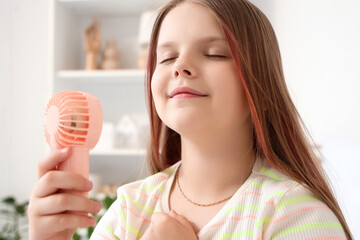 Cute girl with mini fan in bedroom, closeup