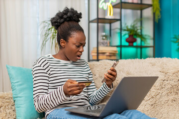 Black woman using laptop and credit card trying to make internet payment feels angry due lack of...