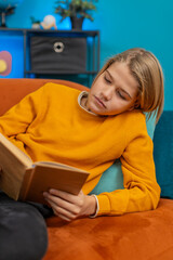 Caucasian teenager boy enjoys reading a book at home. Enthusiastically flips through pages,...