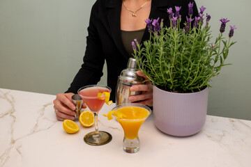 Professional bartending setup featuring cosmopolitan and citrus cocktails on marble countertop,...