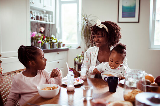 Single mother having breakfast with her two young daughters at home