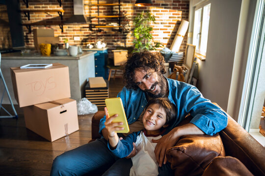 Young father and son taking a selfie after moving in their new home apartment