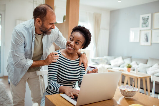Happy couple shopping online with credit card at breakfast table
