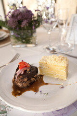 Gourmet gastronomy in a social event. Closeup view of a grilled loin fillet with sauce and a potato mille feuille in a white dish on the gala table
