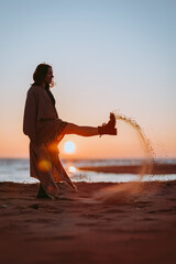woman kicking  sand on the beach silhouette