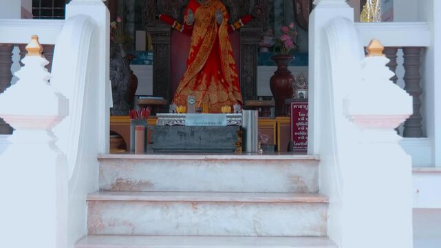 A statue of Goddess Uma Devi (Mother Uma) in colorful orange golden saree stands in the temple in Samut Prakan, Thailand. Shot in motion