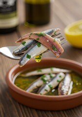 Close Up of Anchovies on Fork Above Bowl with Lemon and Oil Photo