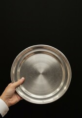 Hand Holding Silver Tray Against Black Background Photo