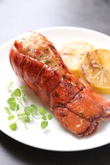 Delicious lobster tail with microgreens and slices of lemon on grey table, closeup