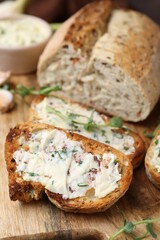 Tasty bread with garlic, herbs and oil on wooden board, closeup
