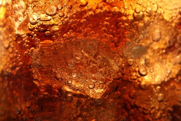 Refreshing cola with ice as background, macro view