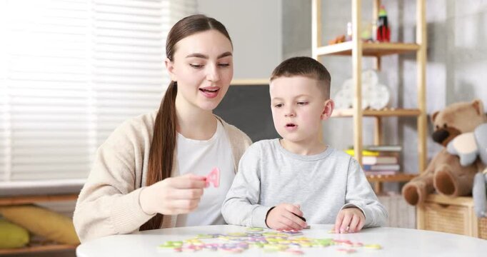 Dyslexia. Mother and her son learning letters at table indoors