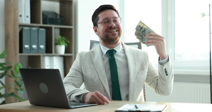 Greedy banker waving money and smiling at table in office