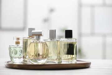 Bottles of perfumes on white wooden table indoors. Space for text