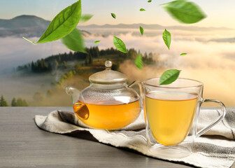 Green tea leaves flying above hot beverage on wooden table in mountains