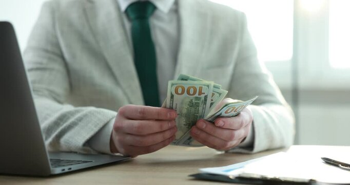 Greedy banker counting money at table in office, closeup