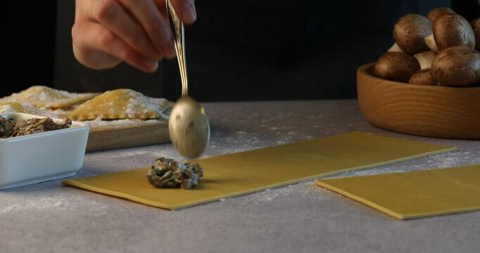 Woman making ravioli with mushrooms at light table, closeup