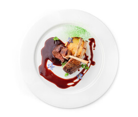 Roasted lamb chops or beef ribs meat with vegetable puree and sauce in plate isolated on white background. Meat dishes, top view, close up