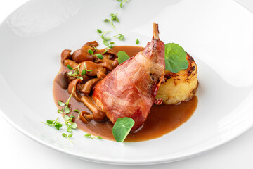 Baked rabbit leg with vegetable puree and mushrooms in plate isolated on white background. Meat dishes, top view, close up