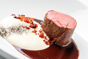 Grilled fillet mignon steak or grilled beef medallion with sauce on plate isolated on white...